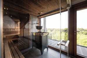 A sauna room with wooden benches, a hanging sauna tub, and a view of the outdoors through large windows. - Wellnesshotel Wittelsbach (Bad Fuessing)