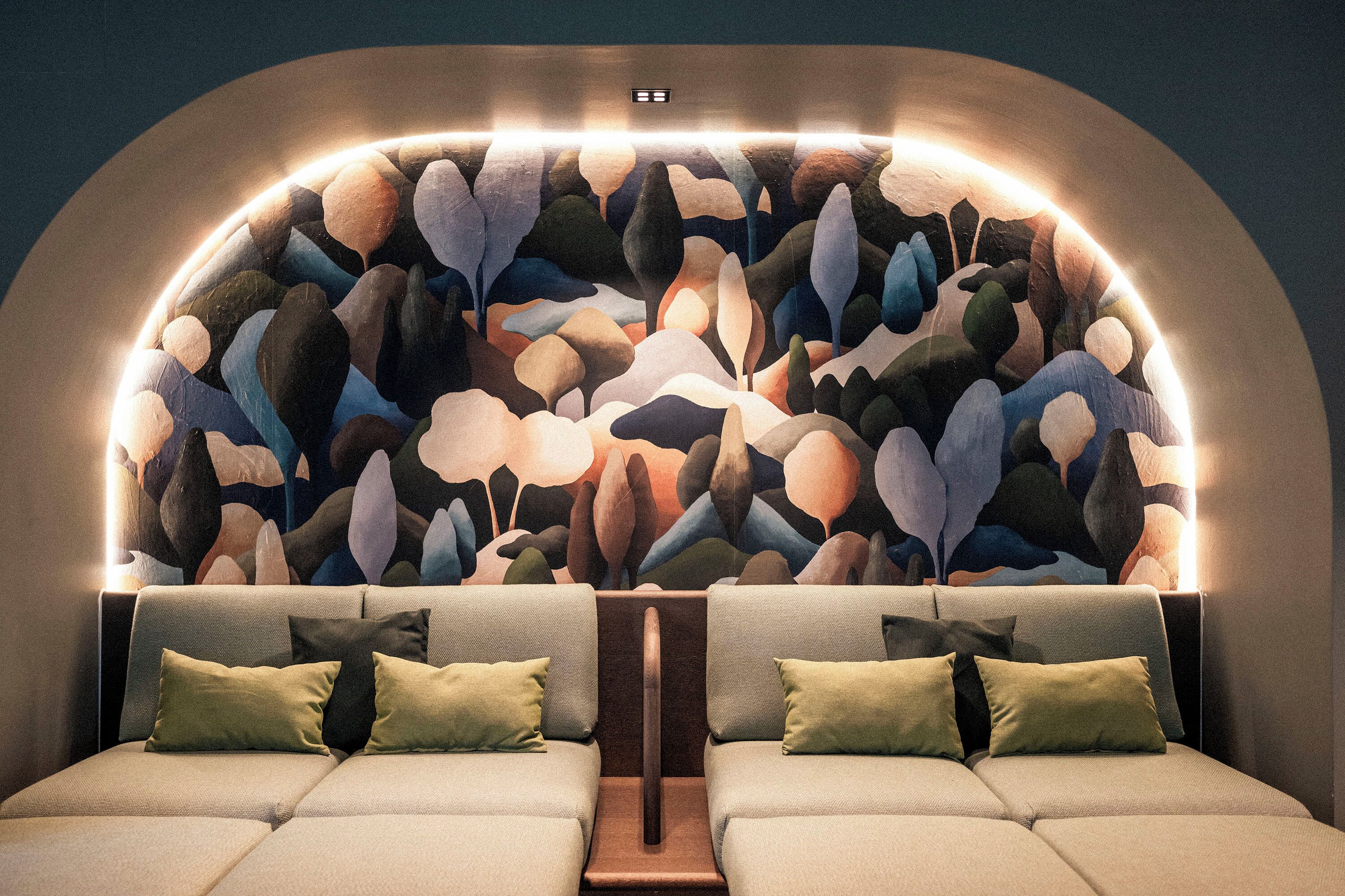 A modern, well-lit bedroom with a unique wall mural, a central wooden panel, and two cushioned seating areas with pillows.