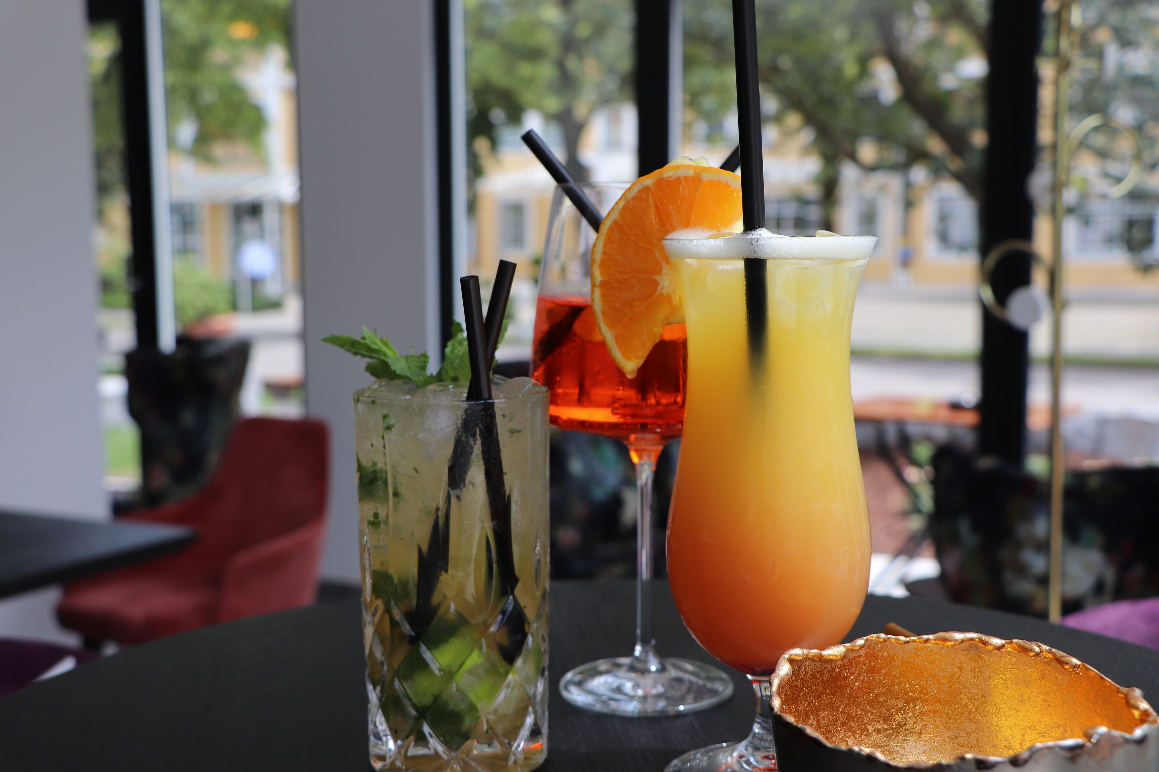 Una mesa con dos bebidas, una con una rodaja de lima y la otra con una rodaja de naranja, y una concha decorativa.