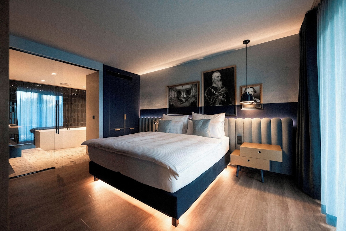 A modern bedroom with a large bed, bedside tables, and artwork on the walls.