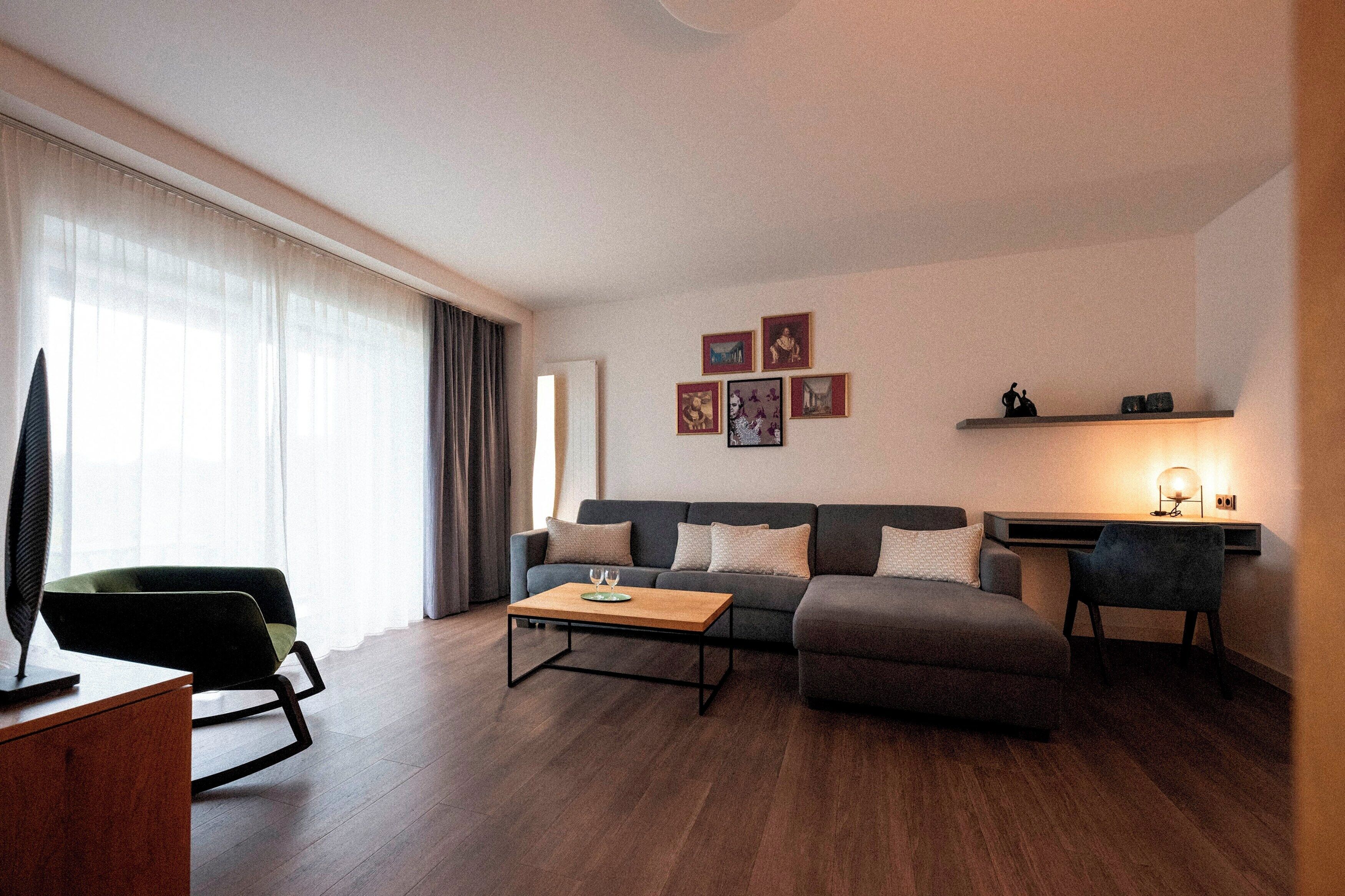 A modern living room with a sofa, a coffee table, a TV, and a desk with a lamp.