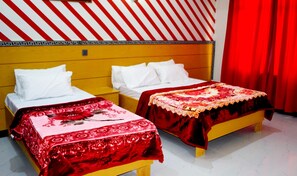 Two single beds with white mattresses and patterned bedspreads, a yellow headboard, and a red curtain adorn this stylish room.