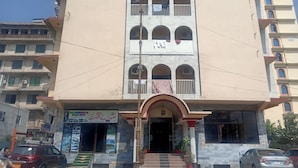 A multi-story building with a central entrance, balconies, and a signboard with text. - Hotel Al Badar (Rawalpindi)