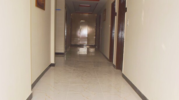 A long, narrow hallway with a marble floor and a red line running along the ceiling. - Hotel Al Badar (Rawalpindi)