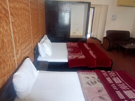 Una habitación con dos camas, un armario de madera, un sofá y una pequeña mesa.