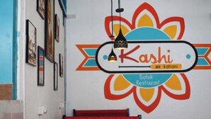 Un interior de restaurante con un logotipo colorido, cuadros enmarcados en la pared y un banco estampado.