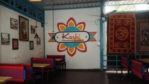 Interior de restaurante con un logotipo central, mesas de madera y bancos rojos con estampado.