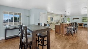 A spacious kitchen with wooden flooring, a central island, and light blue walls. - Wine Country Retreat | Gorgeous Views, Minutes to Wineries (Temecula)