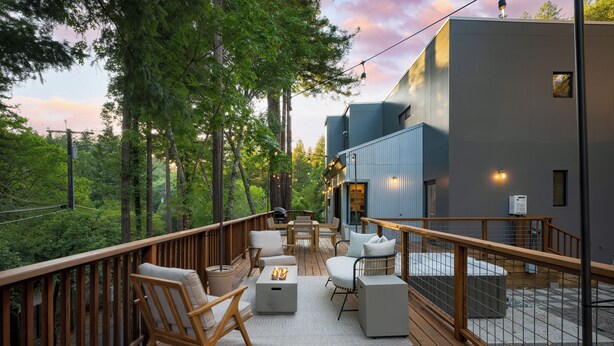 A deck with outdoor furniture, a fire pit, and a view of a modern building. - Mill Creek by AvantStay | Modern Design, Patio, Hot Tub (Healdsburg)