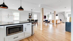 A modern kitchen with a built-in microwave, a dining area with a table and chairs, and a living room with a sofa and a coffee table.