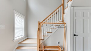 A staircase with wooden steps and a wooden handrail, leading to a landing with a coat rack.