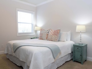 Une chambre à coucher avec un lit, deux tables de chevet, une fenêtre et une lampe.