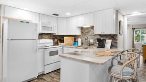 A modern kitchen with white cabinets, a granite countertop, and a built-in stove. - Spacious updated condo with a lake view, private balcony, and $300 Free Activities Daily! (Panama City Beach)