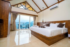 A spacious bedroom with a large bed, wooden headboard, and a balcony with a view.