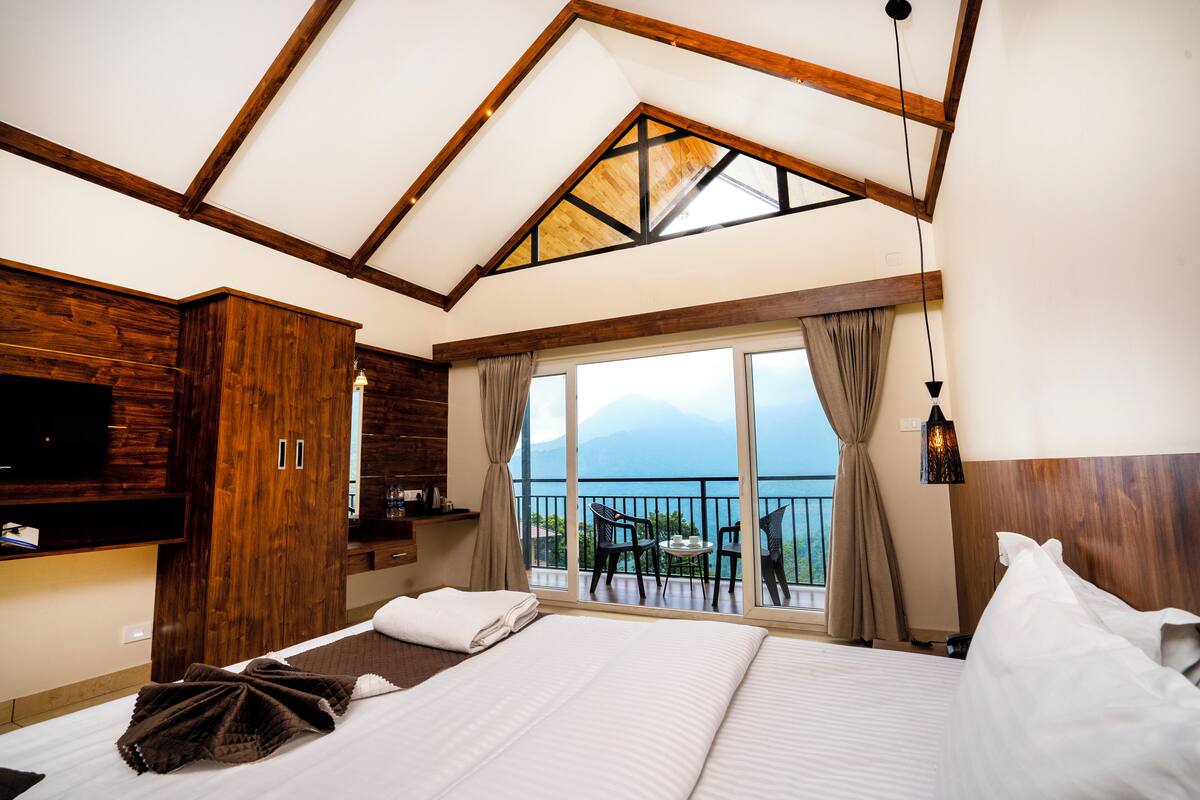 Une chambre dotée d’un grand lit, d’une armoire en bois et d’un balcon offrant une vue sur la mer.