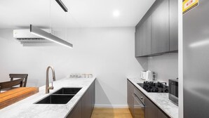A modern kitchen with a marble countertop, stainless steel appliances, and wooden flooring.
