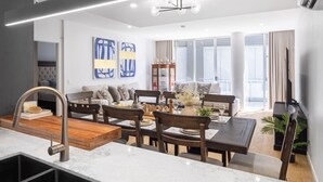 A modern living room with a dining area, featuring a large window, a sofa, and a coffee table.