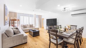 A modern living room with a sofa, coffee table, and dining area with chairs and a table set for a meal.