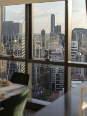 A view from a window with a cityscape, including tall buildings and a clear sky.