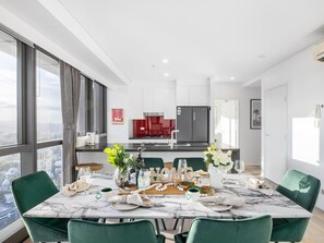 Un espace repas moderne avec une table en marbre, des chaises vertes et une vue sur la ville.