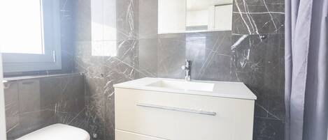Un baño con inodoro blanco, lavabo y espejo.