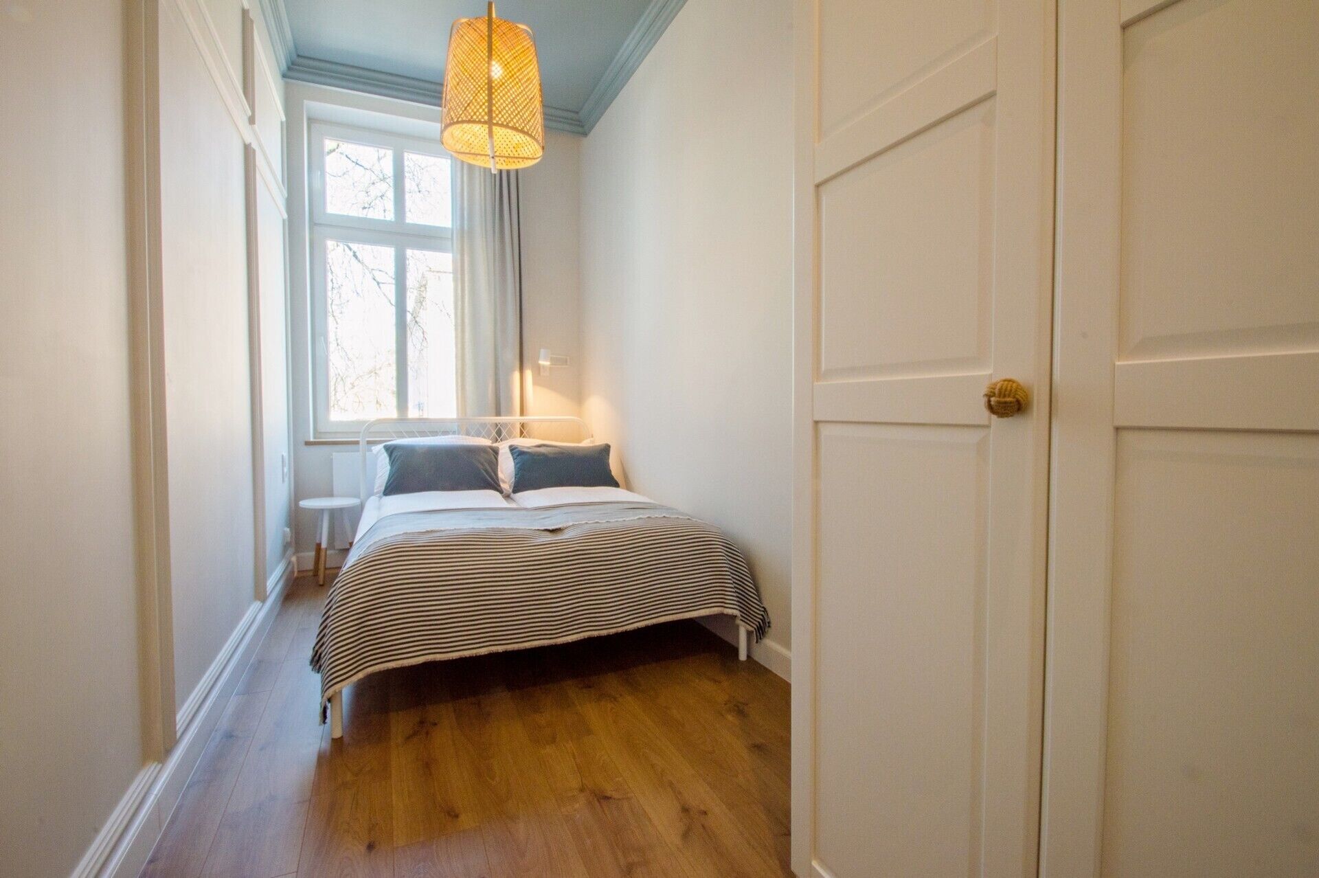 A bedroom with a bed, a window, and a door.