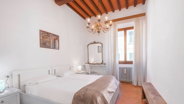 A bedroom with a bed, bedside table, lamp, and a wooden bench. - Chiara Apartment In Porta San Frediano (Florence)