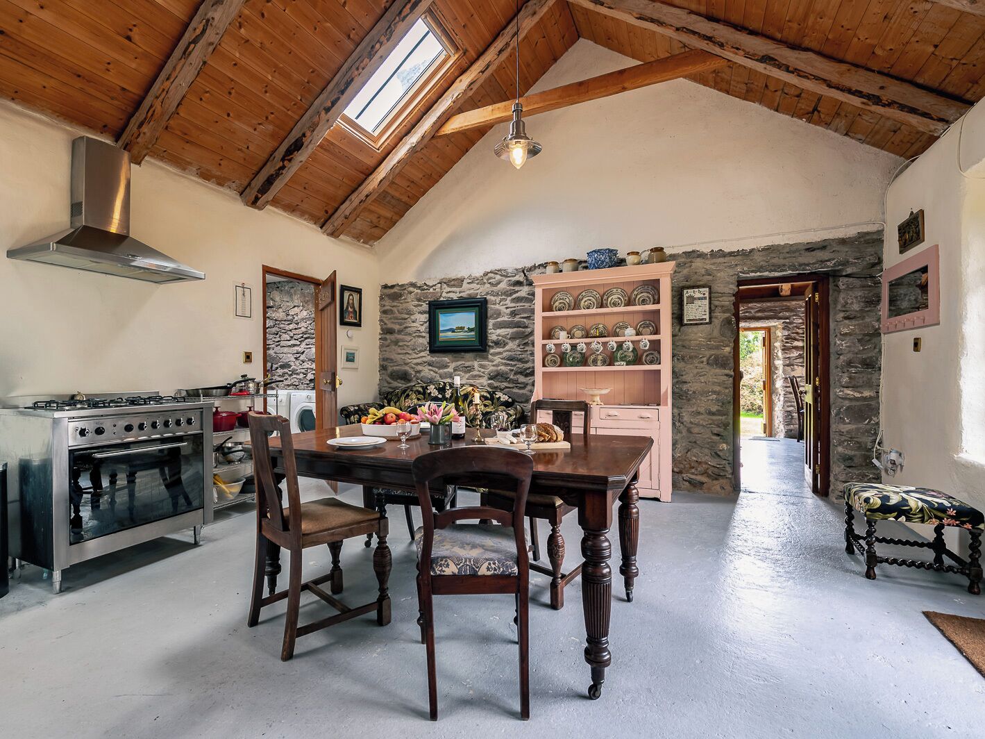 Una cocina rústica con pared de piedra, techo de madera y un comedor con mesa y sillas.