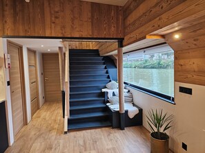 Una escalera de madera que lleva a un rellano con vista al río.