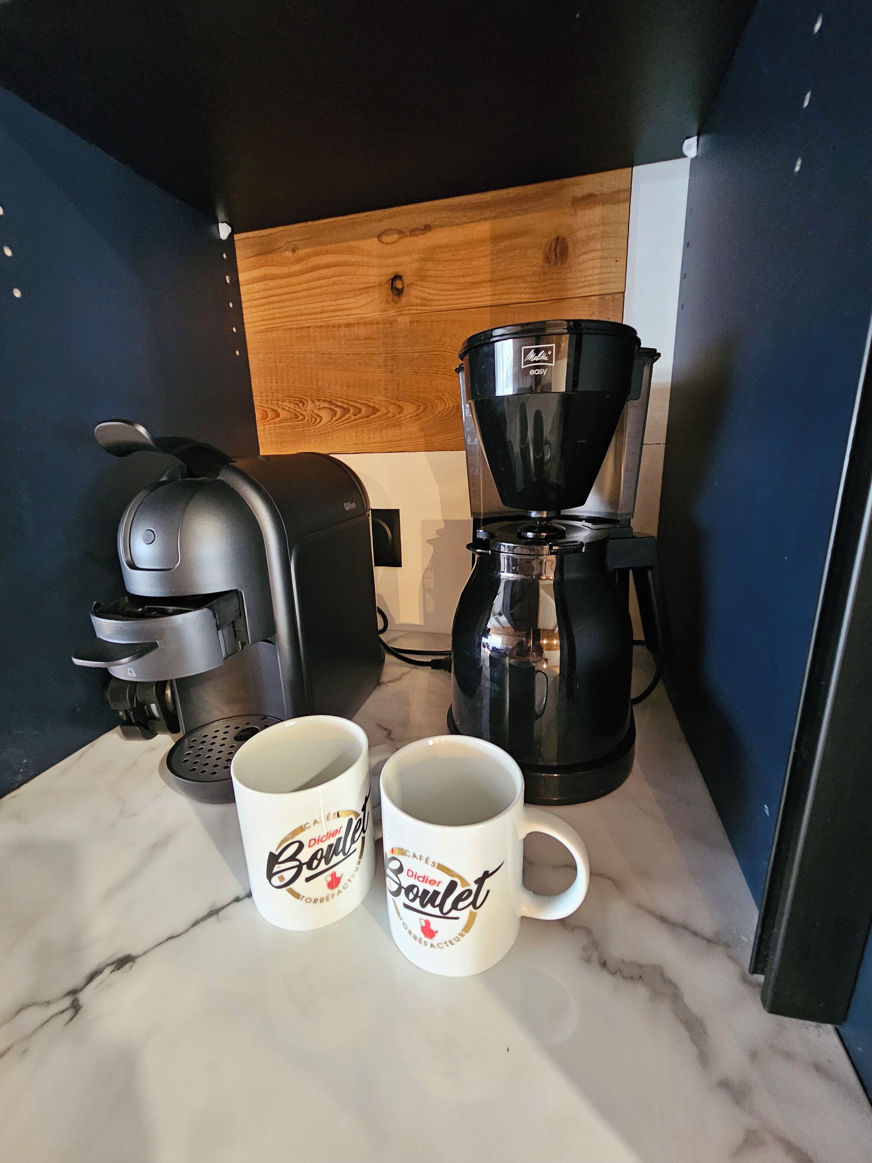 Un comptoir de cuisine avec une machine à café, deux tasses à café et un grille-pain.