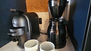 Un comptoir de cuisine avec une machine à café, deux tasses à café et un grille-pain.