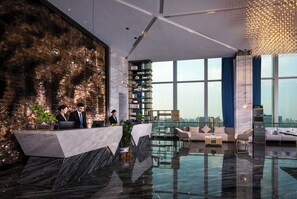 A modern lobby with a reception desk, seating area, and a large window offering a city view. - Songhu Yingbinli Hotel (Dongguan)