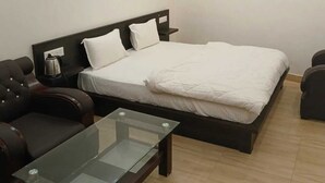 Un dormitorio con cama, una mesita de vidrio y dos sillones de cuero.