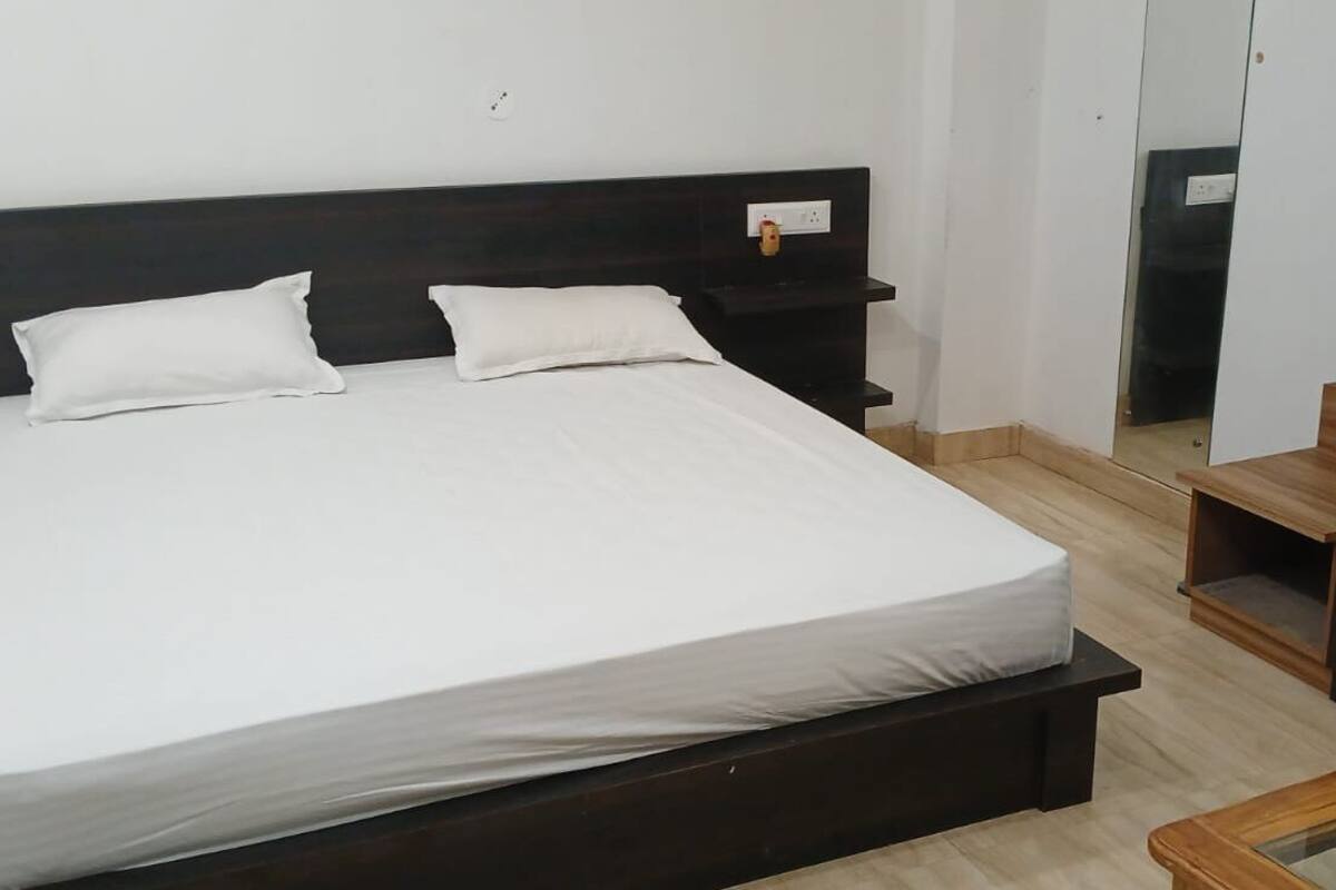 A neatly made bed with white linens and a dark headboard.