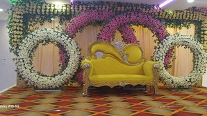 Una habitación con sofá amarillo, adornos florales y suelo estampado.