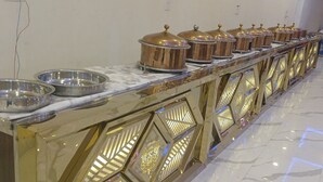 Un montaje tipo bufé con varias estaciones de servicio, cada una con un bol de metal y un recipiente tapado.