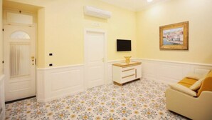 Una habitación con una puerta blanca, un tocador blanco con espejo, un cuadro en la pared y un piso con estampado floral.