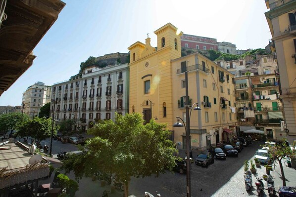 A street view of a historic town with buildings featuring classic architecture, including a church with a bell tower.