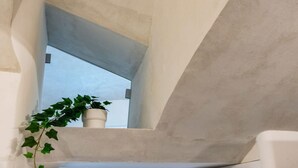 Et moderne interiør med en betonvæg, et lille vindue og en potteplante.
