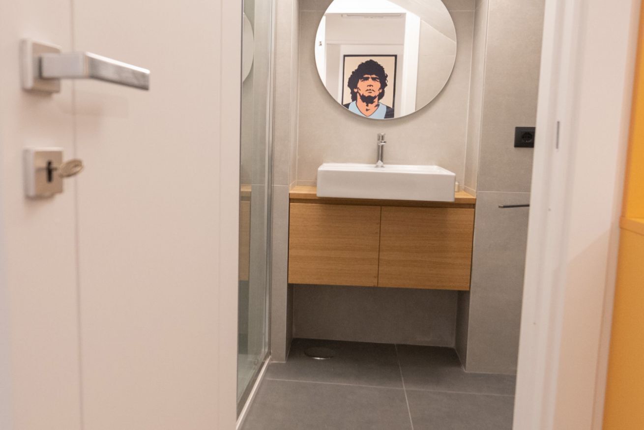 Une salle de bain avec un miroir rond, un lavabo, des meubles en bois et un sol carrelé.