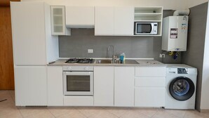 Une cuisine compacte équipée d’une cuisinière à gaz, d’un four, d’un four à micro-ondes, d’un évier et d’un lave-linge encastré.