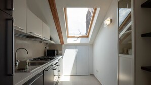A modern kitchen with a skylight, stainless steel appliances, and a white interior.