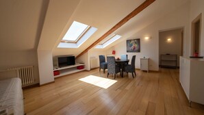 A spacious loft bedroom with skylights, a dining area with a table and chairs, and a kitchenette.