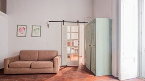 Een kamer met een bruine bank, een groene kast en een deur naar een andere kamer.