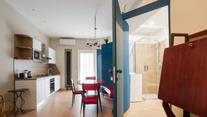 A modern kitchen with white cabinets, a dining table with red chairs, and a visible shower area. - Da Luca e Laura by Dimorra (Napoli)