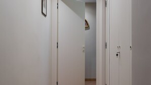 A hallway with white walls and a wooden floor. There is a door on the right and a framed picture on the left wall. - Da Luca e Laura by Dimorra (Napoli)