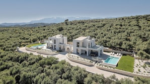 A modern villa with a swimming pool, surrounded by dense greenery and mountains in the background. - Villa Levante With Sea View (Platanias)