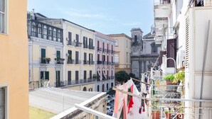 A narrow street with buildings on both sides, balconies with plants, and a clear sky. - Covino House By Dimorra (Napoli)