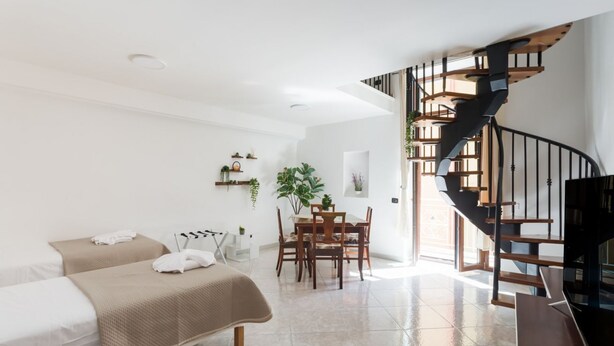 A modern room with a bed, a dining table, and a spiral staircase. - Covino House By Dimorra (Napoli)