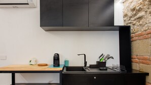 A modern kitchen with a black countertop, a sink, and a coffee maker. - Dimora al Cristo Velato By Dimorra (Napoli)